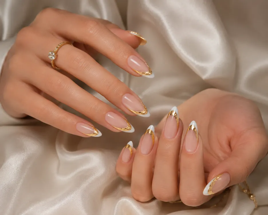 Gold foil French tip manicure with textured metallic leaf over a nude base.