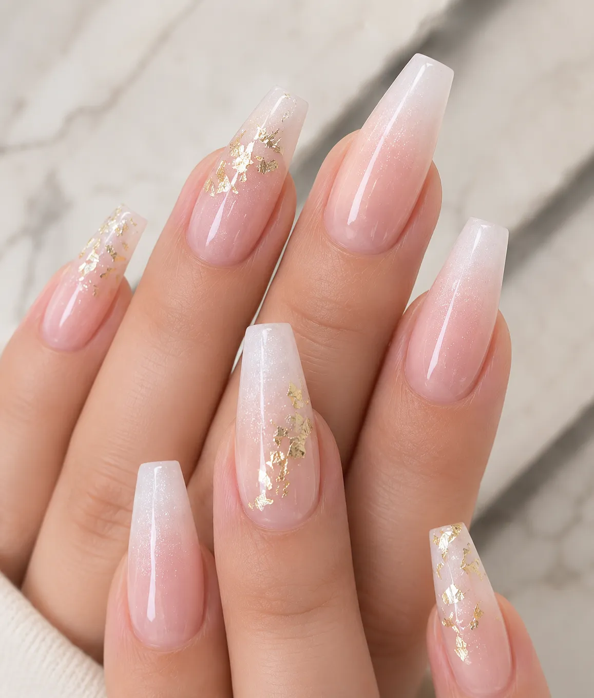 Baby Boomer ombré nails with delicate gold foil fragments on ring finger