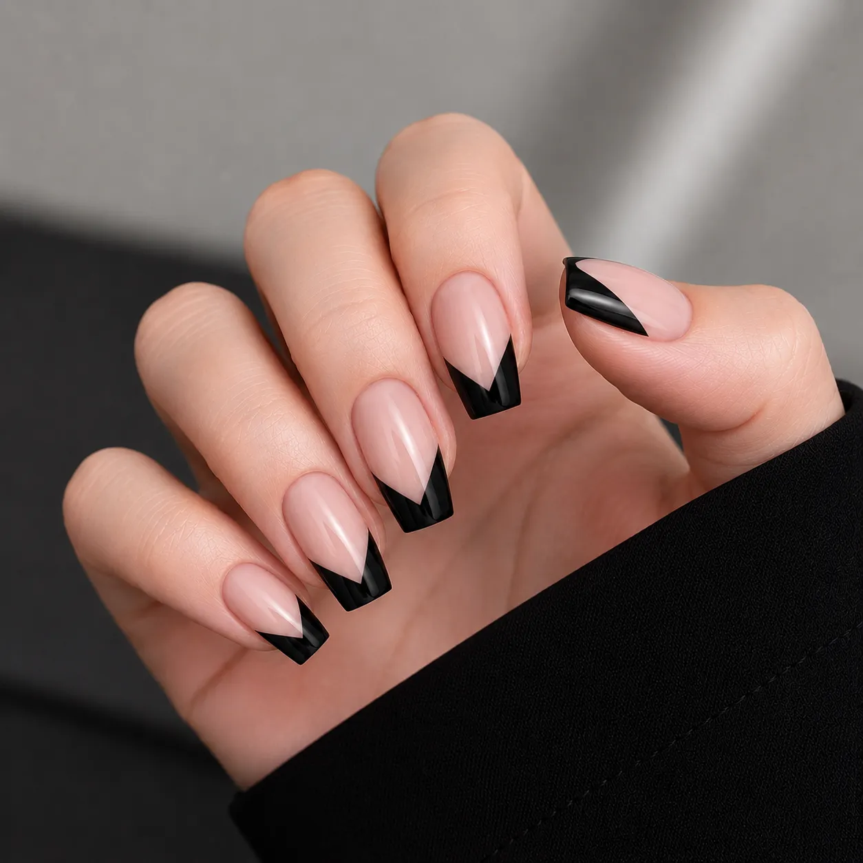 Glossy black V-cut French tip nails on a neutral nude base
