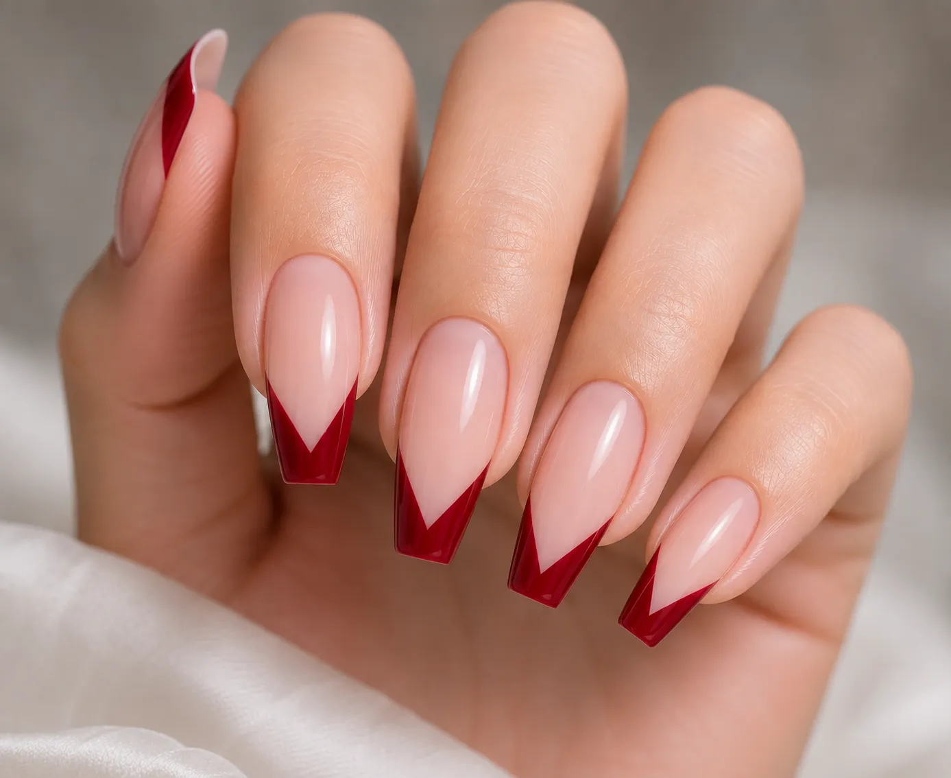 Deep red V-cut French tip nails with a glossy nude base