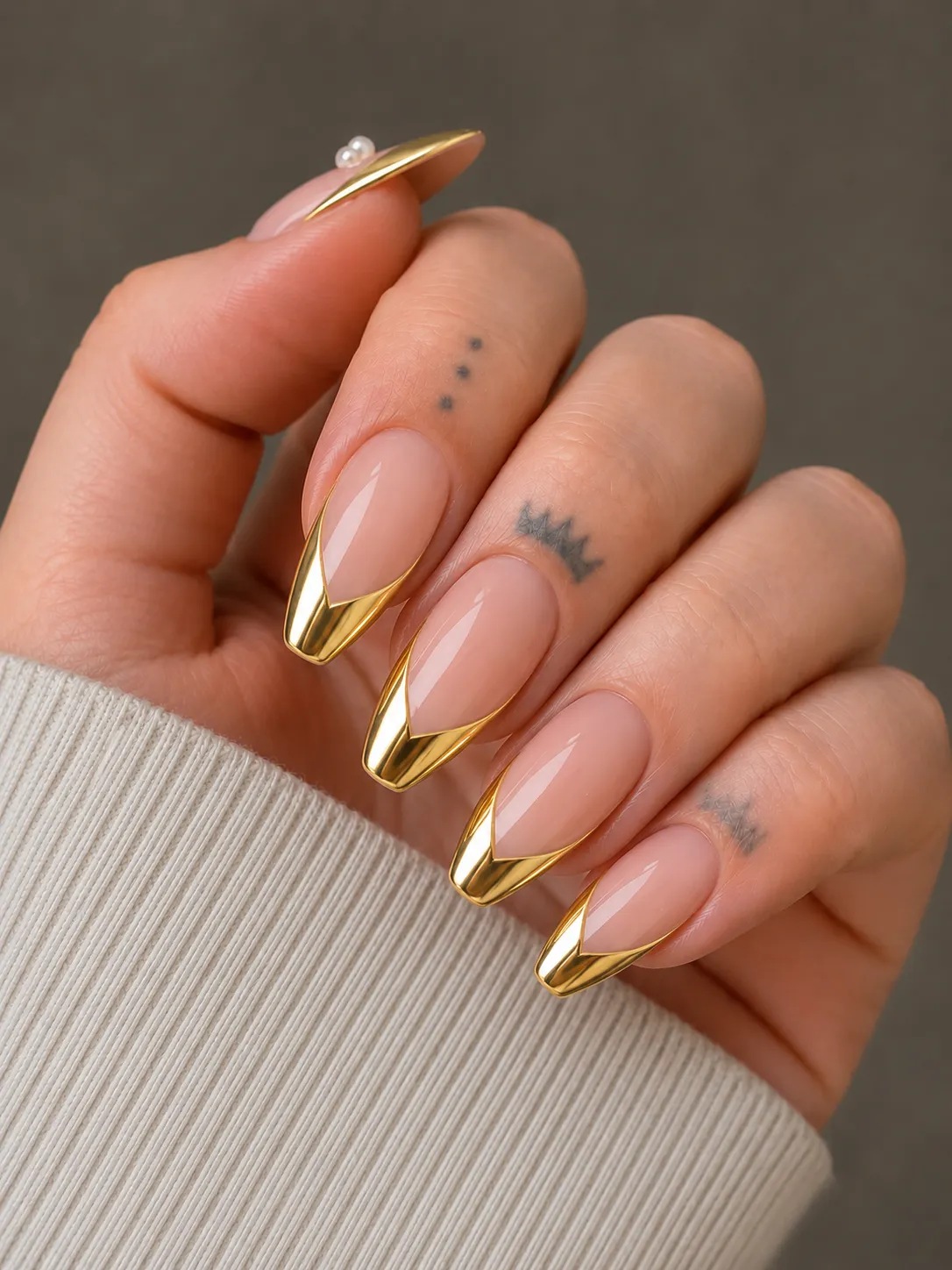 Metallic gold V-cut French tip nails on a sheer blush base