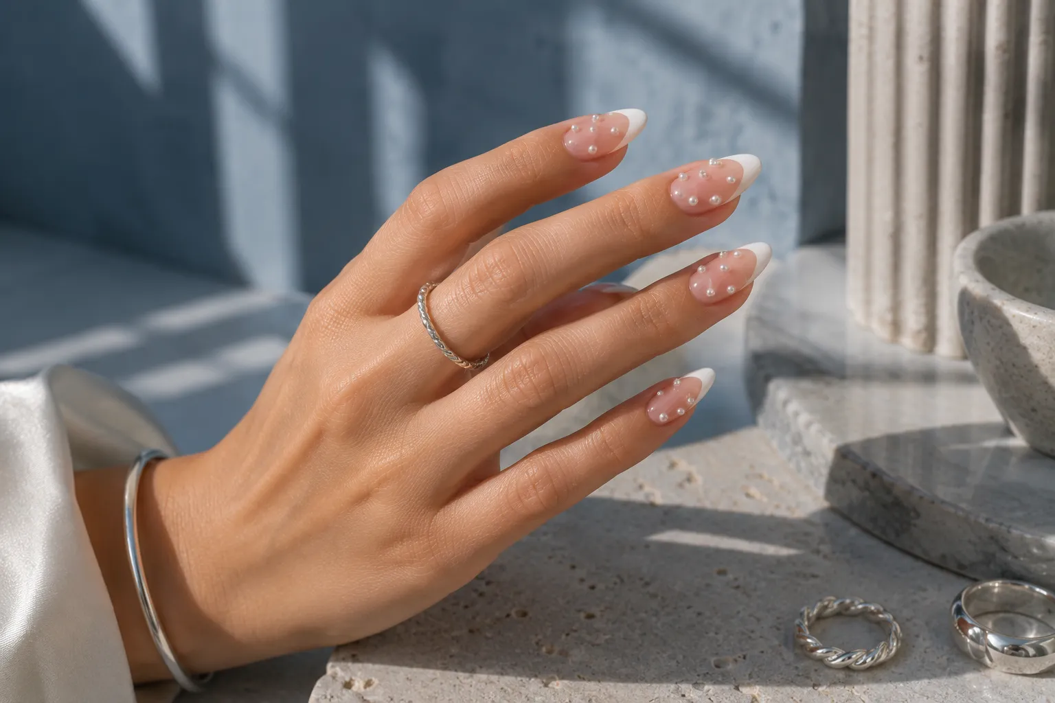 Milky pink almond French nails with sparse asymmetrical micro pearl accents