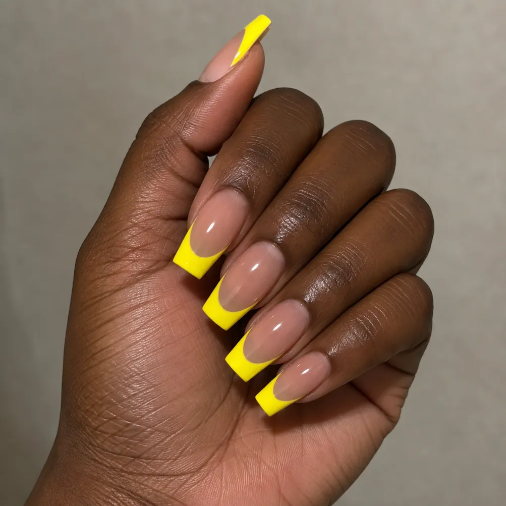 Bright yellow French tip nails creating strong contrast against a deep-looking base tone